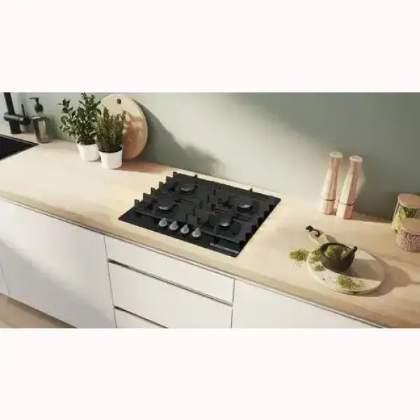 Piano cottura Bosch nero a cinque fuochi integrato in cucina moderna con piano in legno chiaro