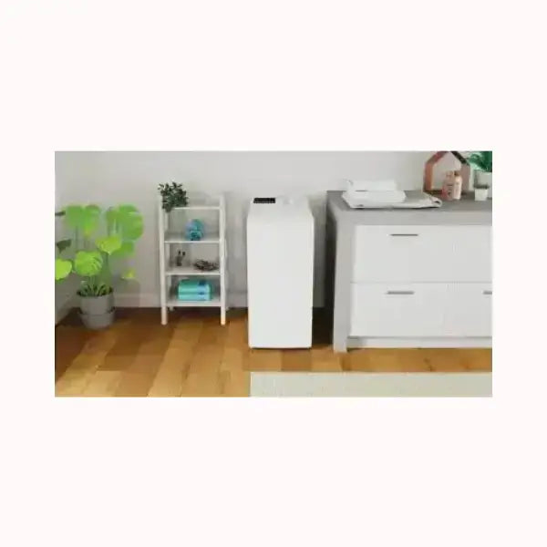 Lavatrice indesit bianca a carica dall'alto collocata in un ambiente domestico con pavimento in legno e mobili bianchi